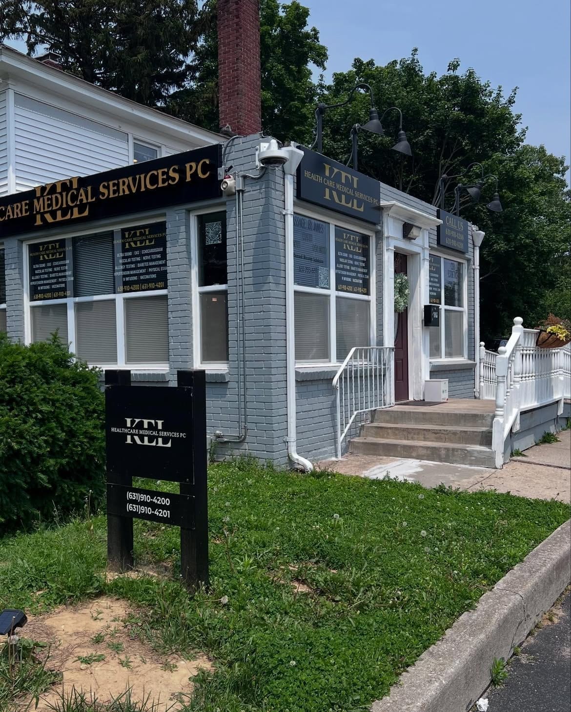 The Wading River clinic seen from the roadside, with the Kel Healthcare Medical Services yard sign and the phone numbers for the practice.